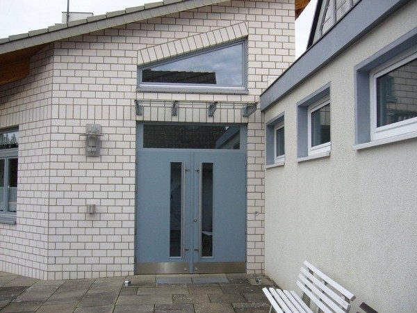 Eingang mit weißer Klinkerfassade und Glastür